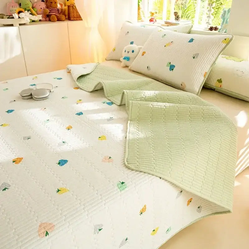 A soft light green cotton quilted bed cover set with colorful fruit motifs neatly draped over a bed