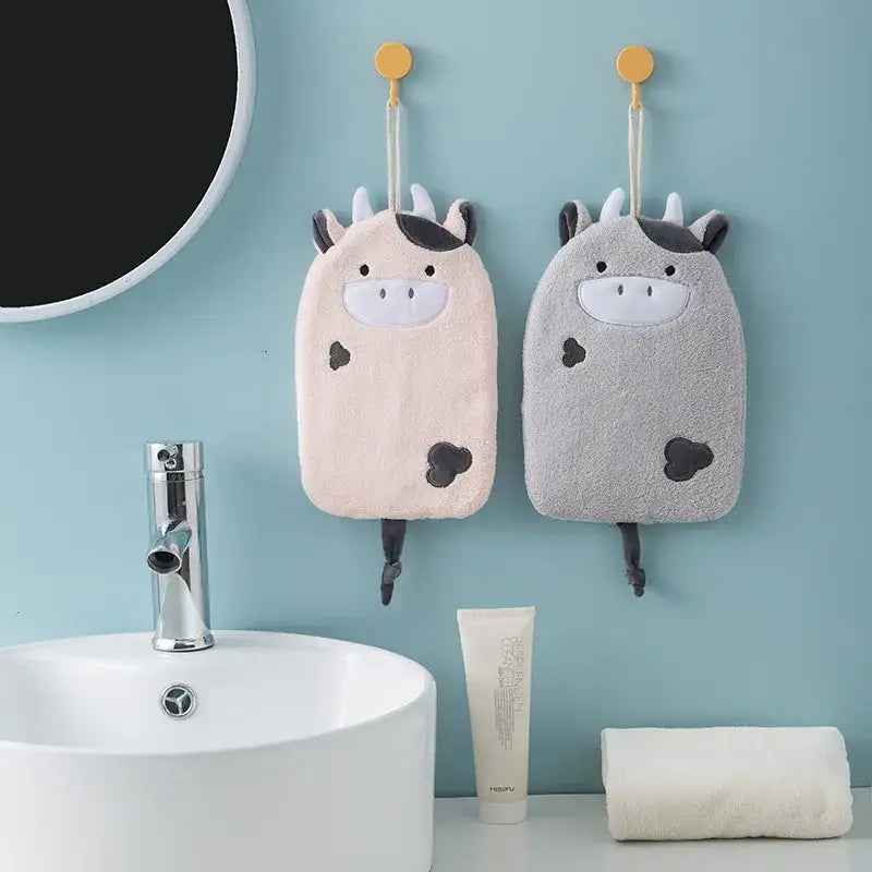 Two plush cow-shaped bath sponges in cream and gray with decorbites cartoon embroidery hanging hand towel design