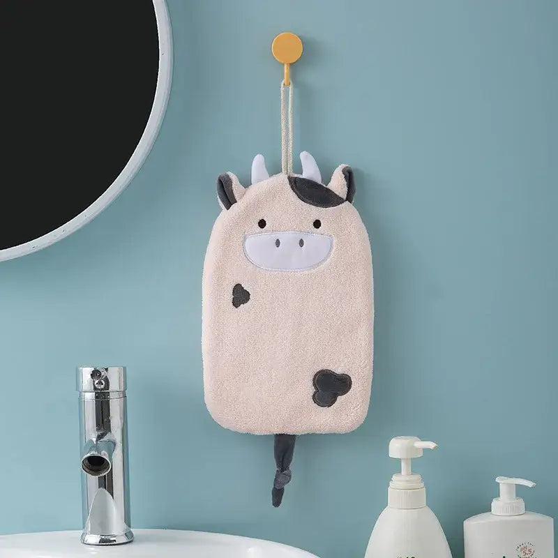 A soft plush cow-shaped bath sponge with black spots hangs from a yellow hook as decorbites cartoon embroidery hand towel