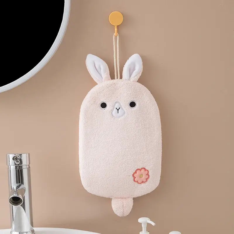 A soft pale pink cartoon embroidery hanging hand towel shaped like a bunny with white ears and embroidered flower decorbites