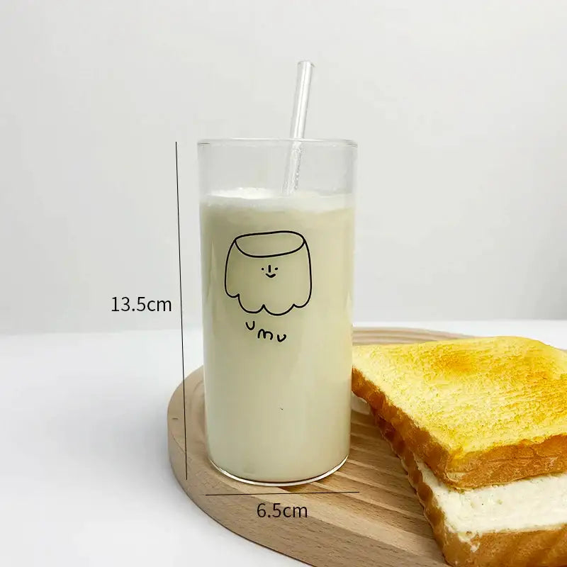 Clear glass cup with a minimalist black cartoon glass cup design filled with creamy milk and a transparent straw