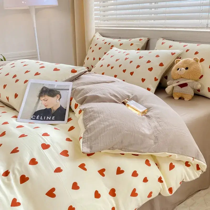 Cream-colored duvet set with cartoon heart floral pattern paired with matching pillows and gray quilted blanket