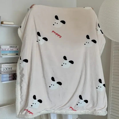 A soft cream-colored cartoon lamb wool blanket with playful black and white puppy faces and red puppy script decorbites cartoon lamb