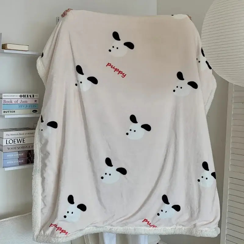A soft cream-colored cartoon lamb wool blanket with playful black and white puppy faces and red puppy script decorbites cartoon lamb