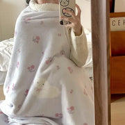 Soft white cartoon lamb wool blanket with pink floral and cloud patterns wrapped around a person taking mirror selfie