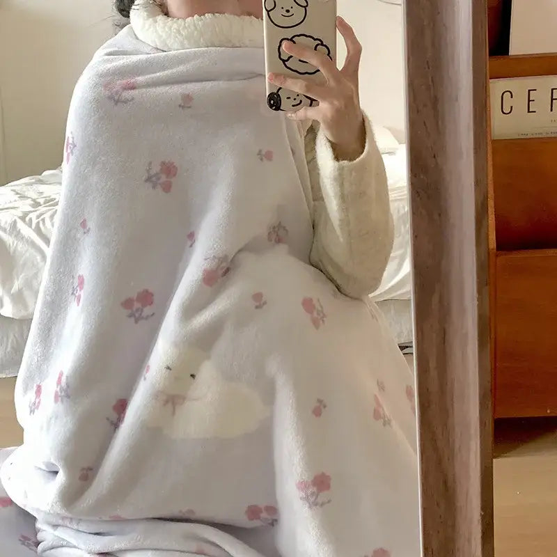 Soft white cartoon lamb wool blanket with pink floral and cloud patterns wrapped around a person taking mirror selfie