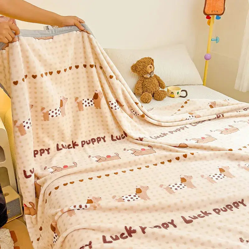 A cream-colored cartoon milk velvet fleece blanket with playful puppies brown hearts and lucky puppy text for decorbites
