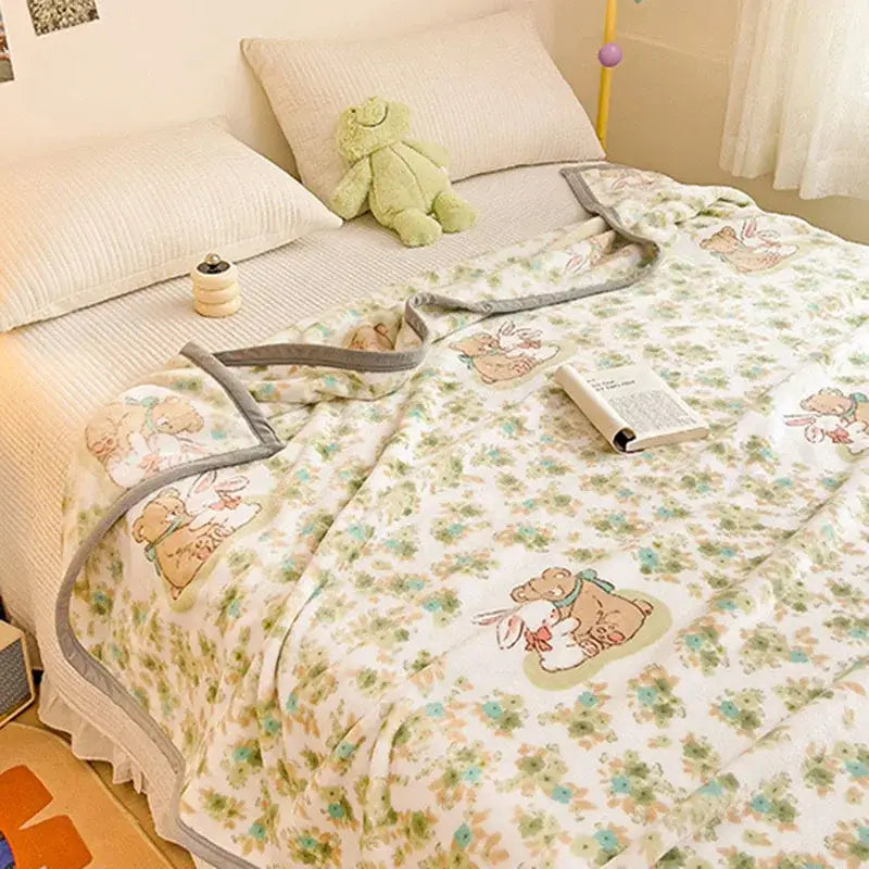 A soft white cartoon milk velvet teddy bear blanket with green and blue floral pattern for bedroom decorbites decor