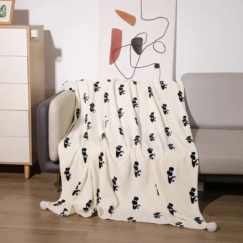 Cream-colored cartoon panda flannel double fleece blanket with black silhouette patterns draped over a sofa decorbites cartoon panda