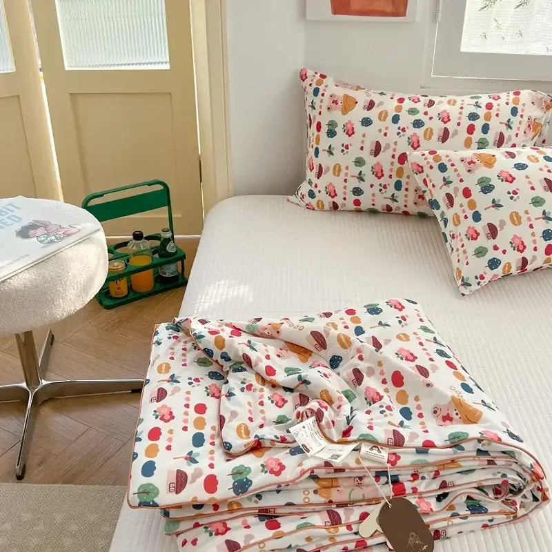 A folded white cartoon patchwork summer cooling blanket with colorful cartoon fruits and vegetables pattern