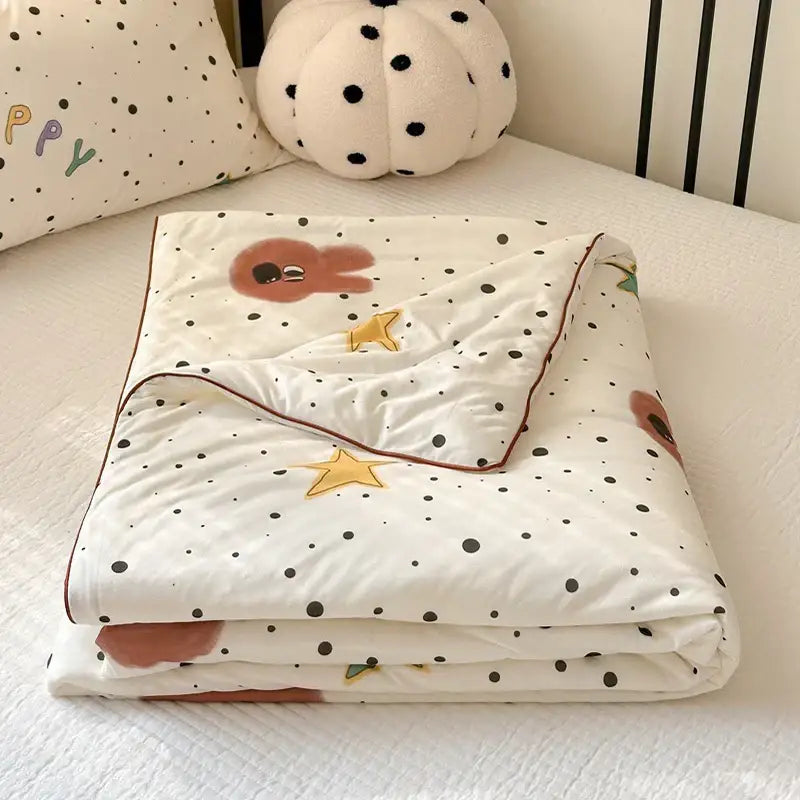 A soft white cartoon patchwork summer cooling blanket with black polka dots brown sleepy characters and golden stars