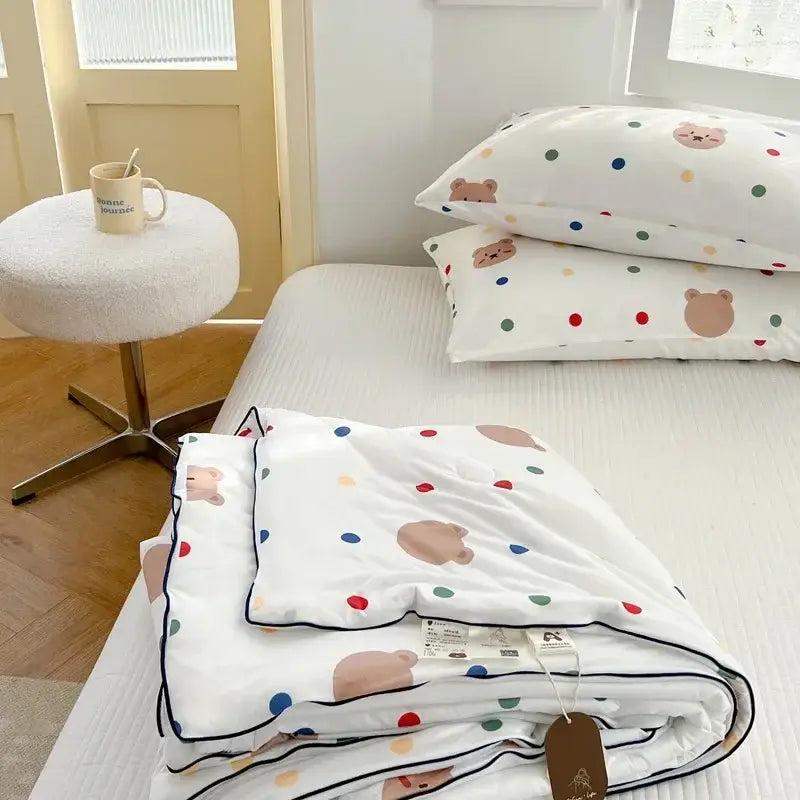 White quilt with colorful polka dots and beige bear faces neatly folded featuring decorbites cartoon patchwork summer design