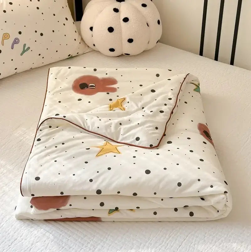 A soft white quilted cartoon patchwork summer blanket with black polka dots, embroidered bunny faces, and golden stars