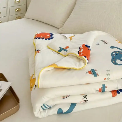 White cartoon patchwork summer cooling blanket with colorful dinosaur and train prints and yellow border by decorbites