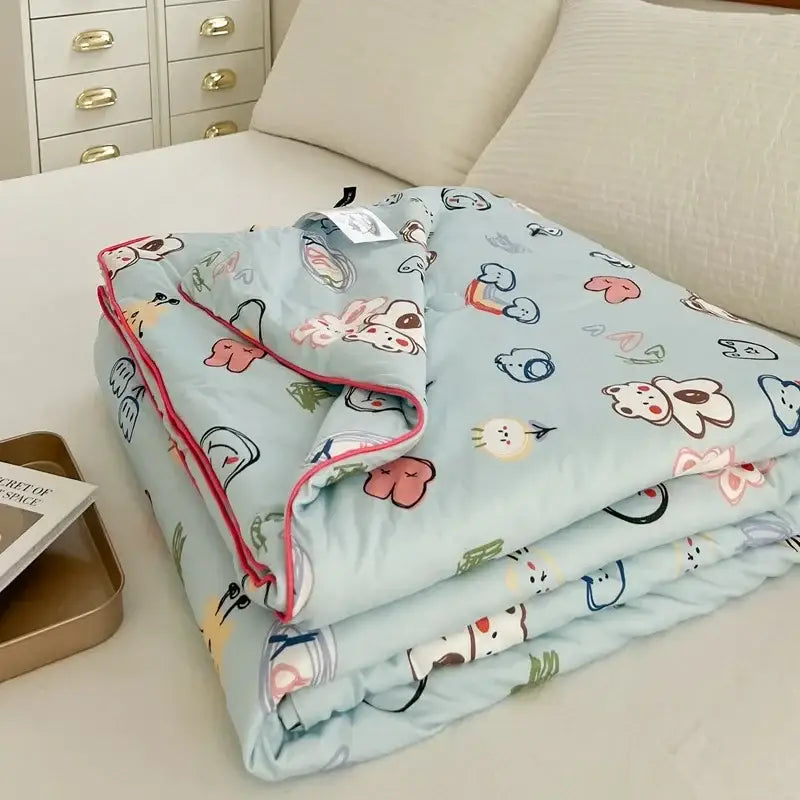 Light blue cartoon patchwork summer cooling blanket with playful animal and heart patterns and pink piping edges by decorbites