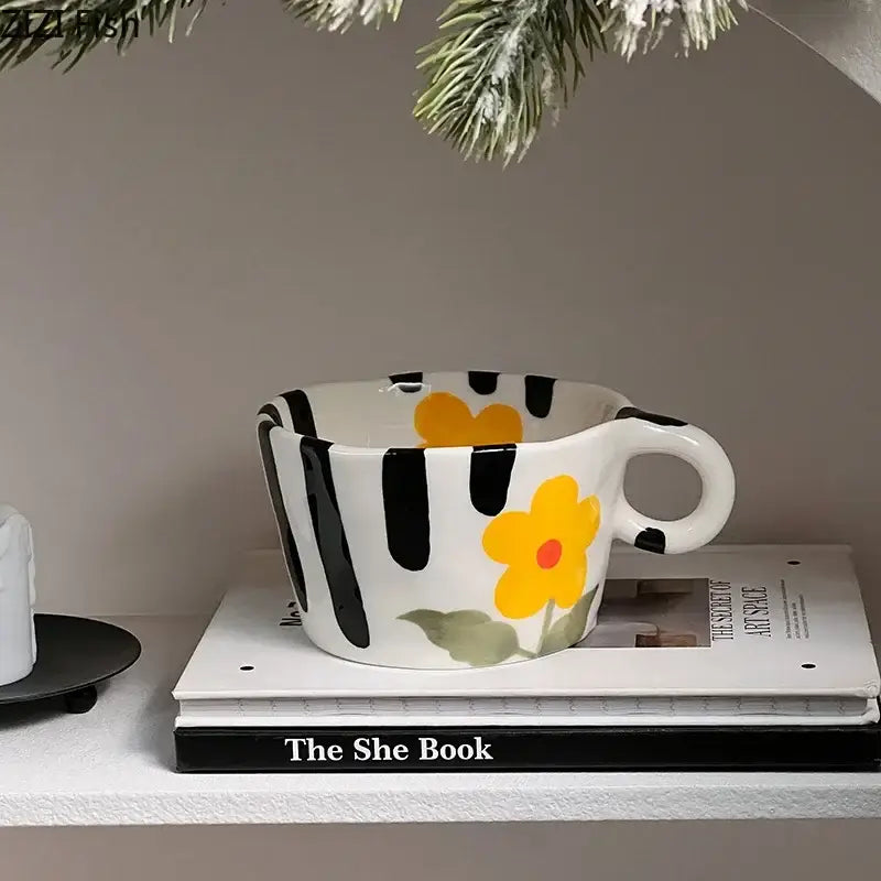A white ceramic mug with bold black vertical stripes and a yellow flower decorbites cartoon pattern ceramic coffee mug