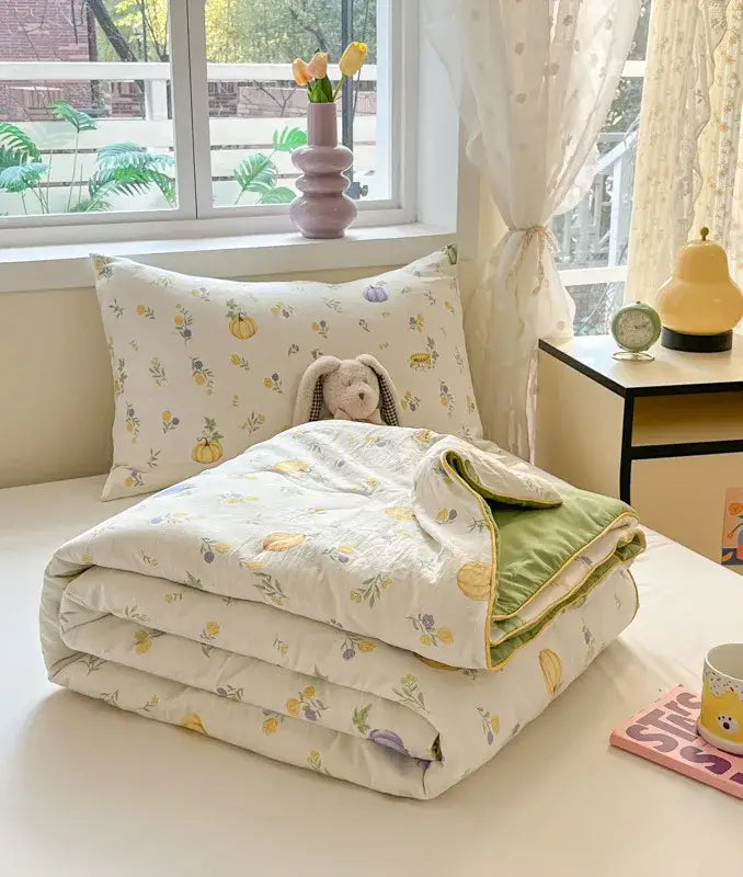 A cream cooling blanket with yellow and purple floral cartoon printed design and green velvet lining for summer use