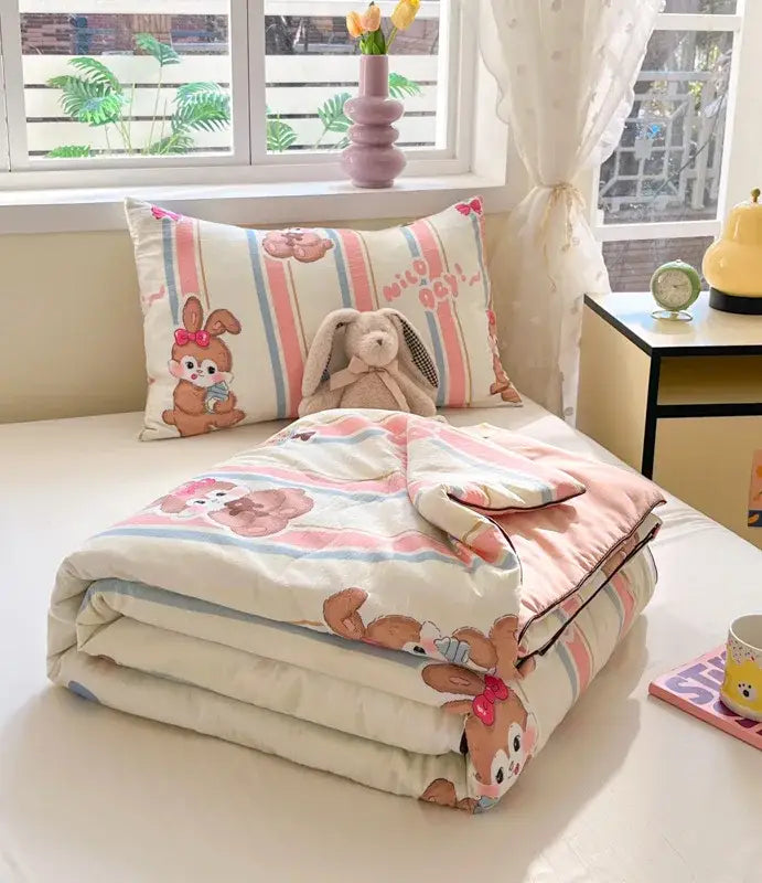 Pastel pink and cream striped cooling blanket with decorbites cartoon printed bunnies in red bows for summer use