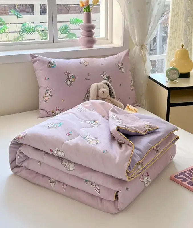A soft lavender decorbites cartoon printed cooling blanket with bunny pattern and gold trim for summer bedroom use