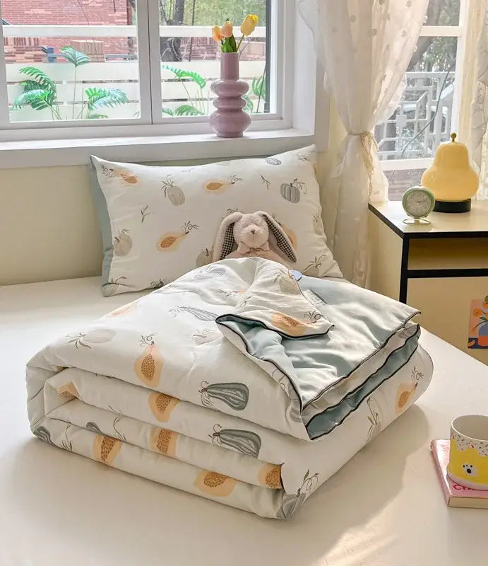A cozy folded decorbites cartoon printed cooling blanket with white and muted orange fruit pattern for summer use