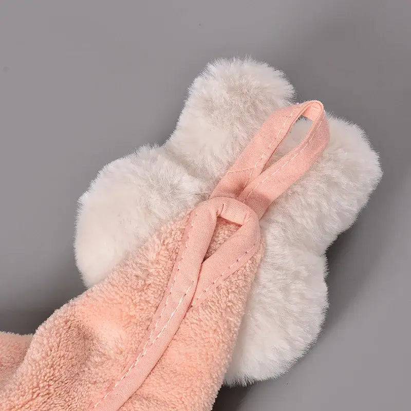 A soft pink coral fleece hand towel with a fabric loop rests on a fluffy white cartoon rabbit bath mitt decorbites cartoon rabbit