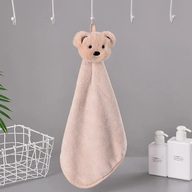 A blush-pink plush hand towel with a cartoon rabbit head and black embroidered eyes made of coral fleece terry cloth