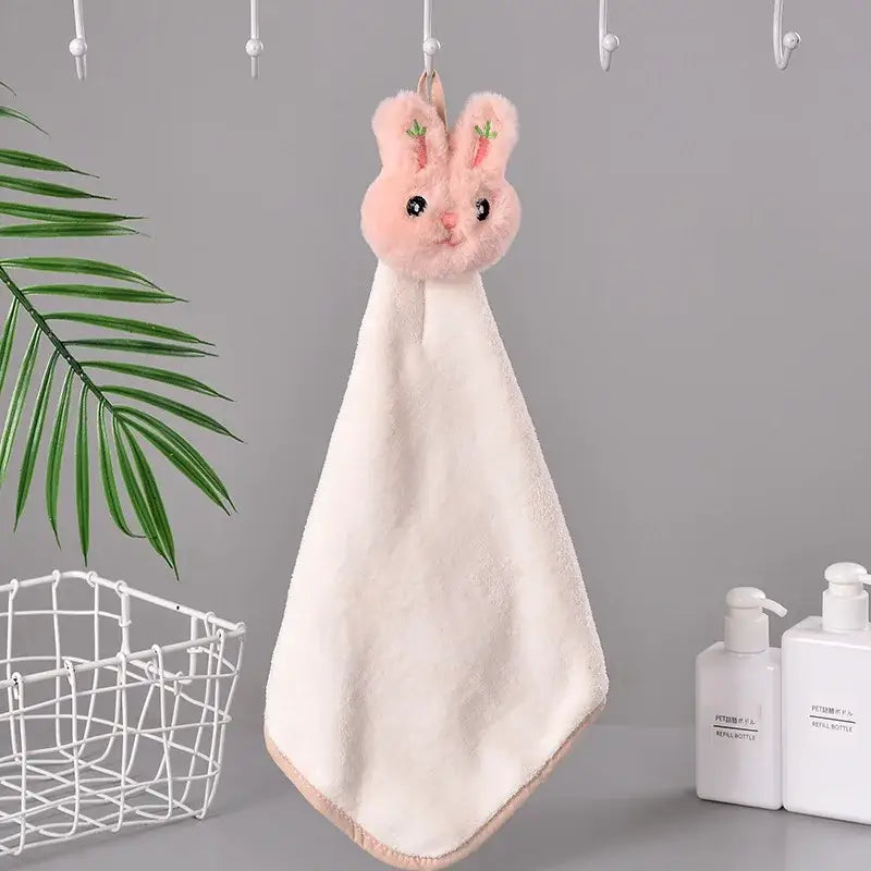 A soft pink coral fleece hand towel shaped like a cartoon rabbit with embroidered carrot details for quick dry use