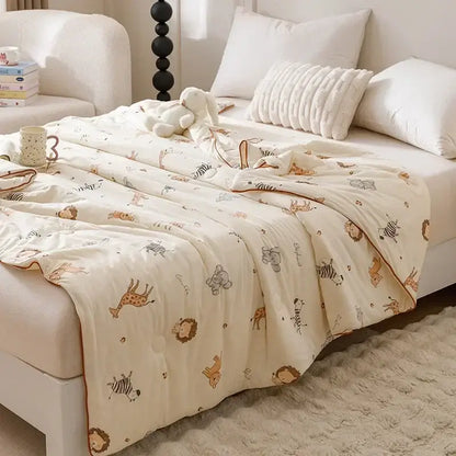 Cream-colored cotton cooling summer blanket with playful animal prints including giraffes zebras and lions in soft tones