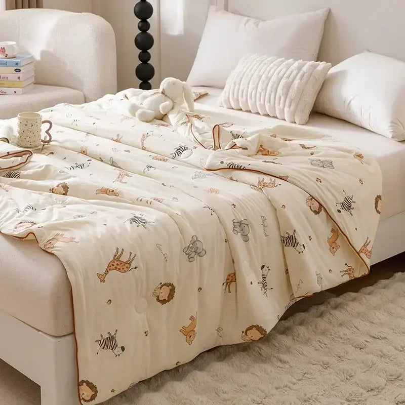 Cream-colored cotton cooling summer blanket with playful animal prints including giraffes zebras and lions in soft tones