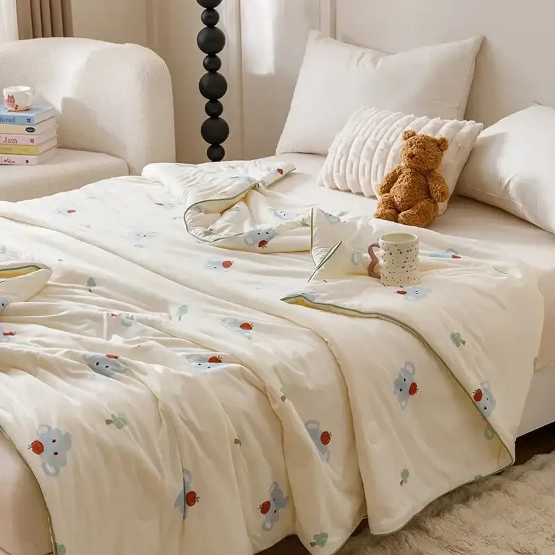 Cream-colored quilted cooling summer blanket with plush texture and embroidered cartoon mice holding strawberries pattern