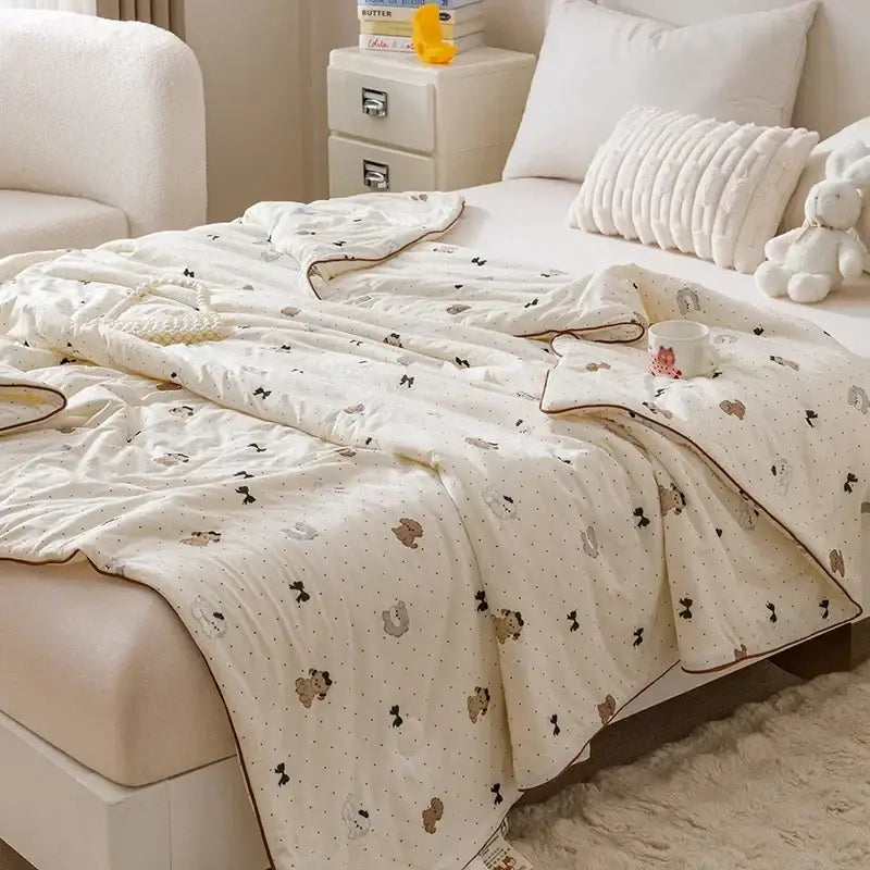 Cream-colored quilted cooling summer blanket with plush texture featuring cartoon bears and bows in muted brown tones