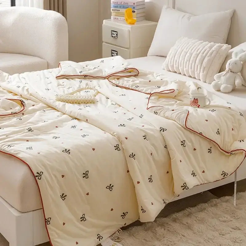 Cream-colored quilted cartoon rabbit off white cooling summer blanket with black bow heart patterns and red piping edges