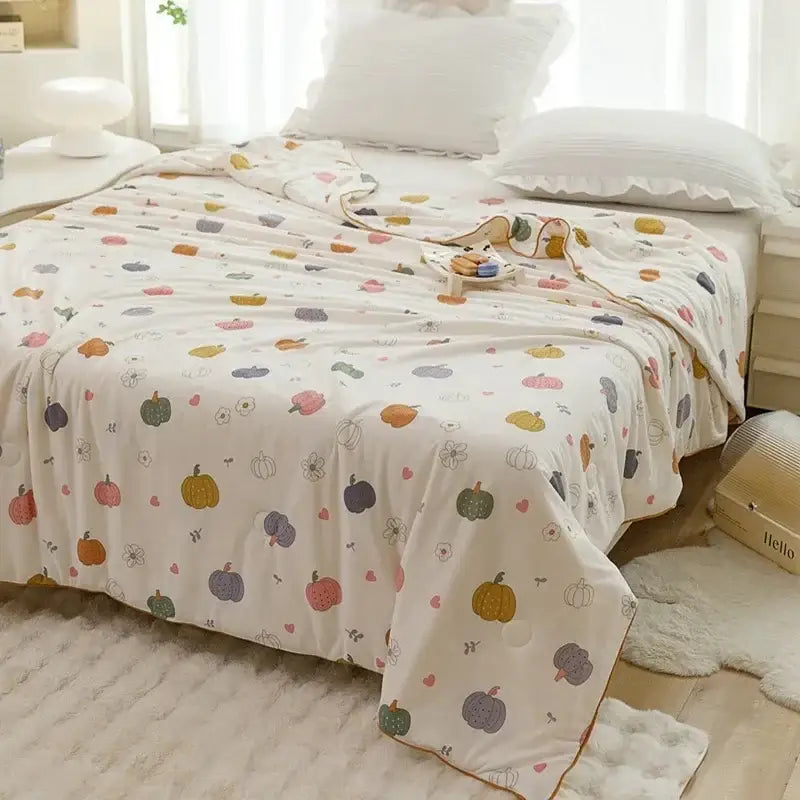 A soft off white cotton cooling summer blanket with multicolored pumpkin and flower patterns for bedroom use