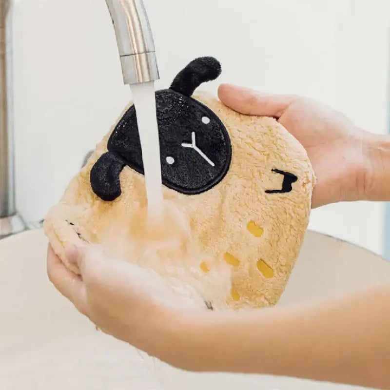 A plush tan sheep-shaped sponge with black embroidered features and yellow spots in decorbites cartoon sloth hand towels set