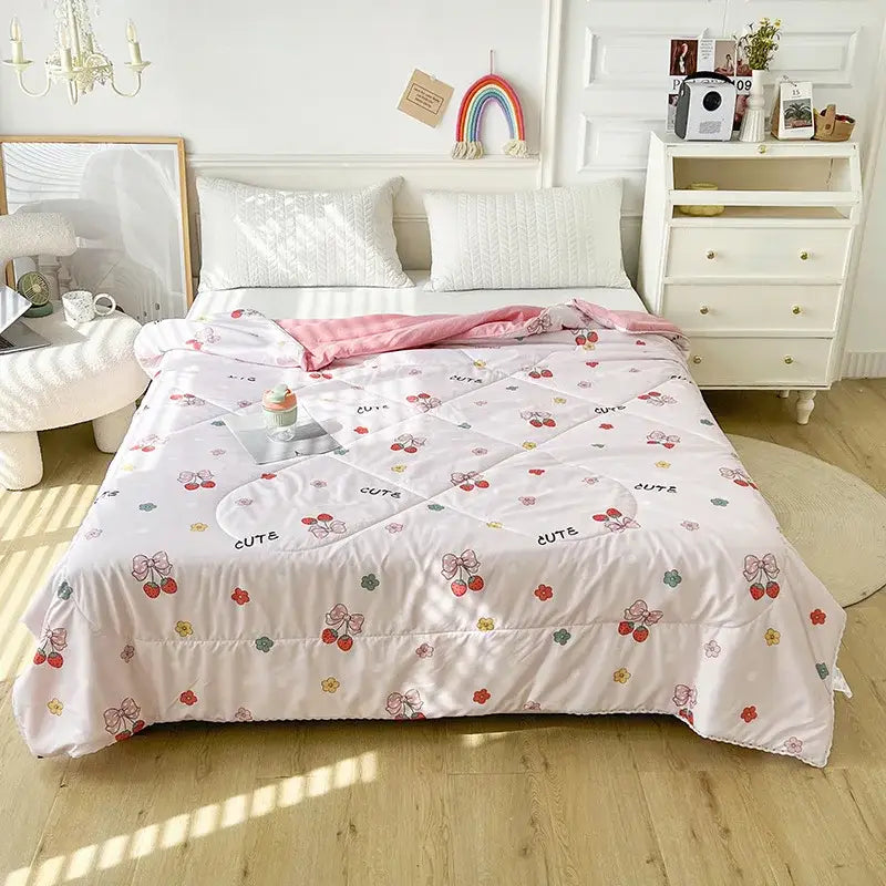 Pink quilted double blanket featuring a playful cherry and bow pattern with the word cute in soft pastel tones
