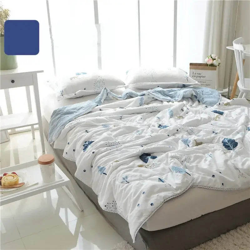 White quilted double blanket with delicate blue embroidered leaf patterns and soft textured fabric finish for bedroom use