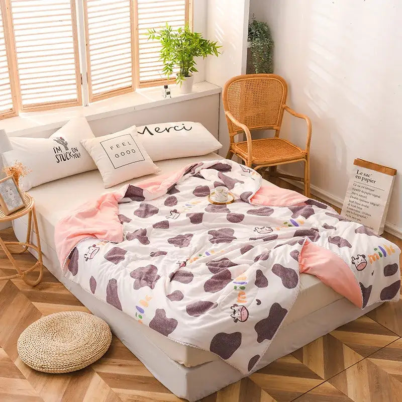 White and pink cow-print fleece quilted double blanket with soft plush texture for bedroom use