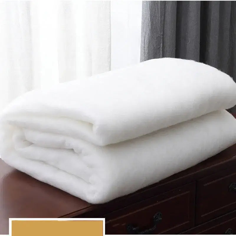 White plush faux fur quilted double blanket neatly folded on wooden surface for bedroom use