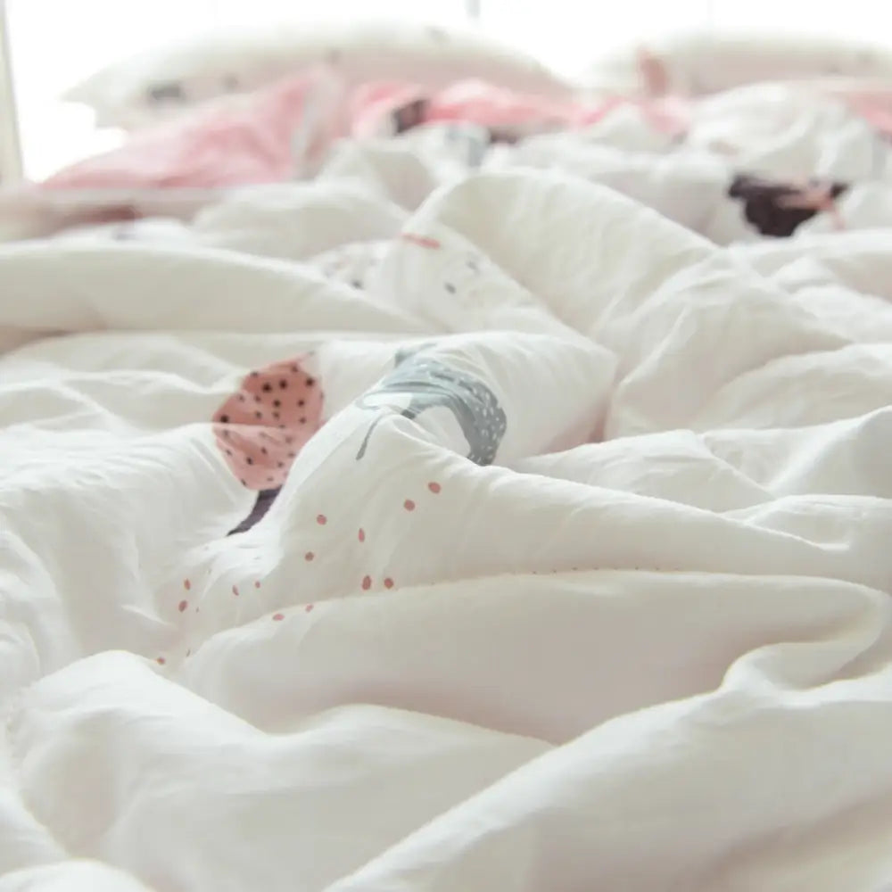 A soft white quilted double blanket with playful pink and gray polka-dotted animal prints for bedroom use