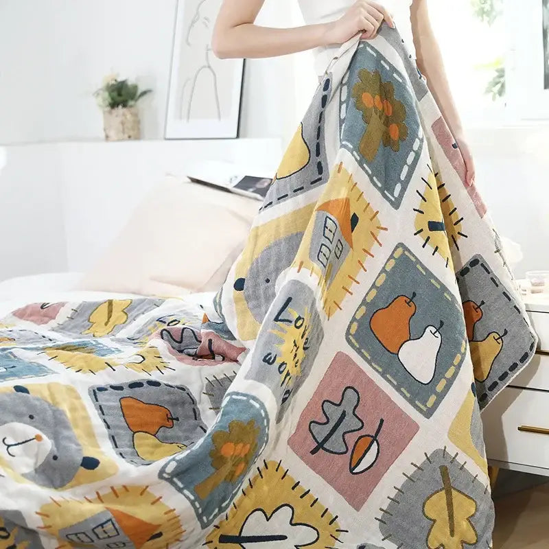 A decorbites cartoon throw blanket in muted yellows and grays with playful patchwork of animals and autumn motifs