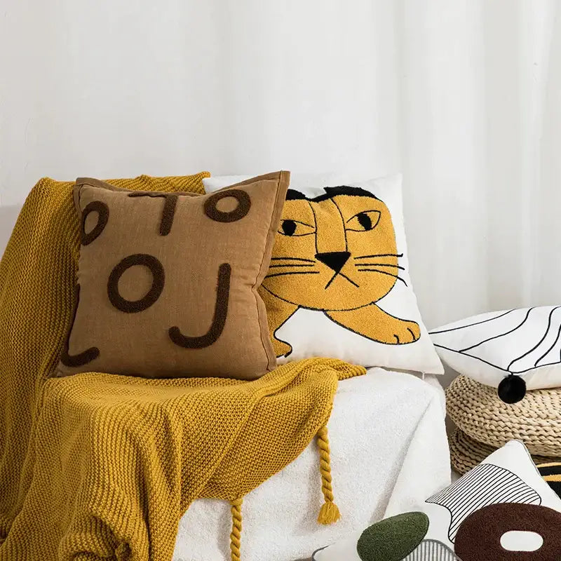 Cozy mustard-yellow knitted throw blanket with tassels draped over white chair near decorbites cartoon tiger pillow cover
