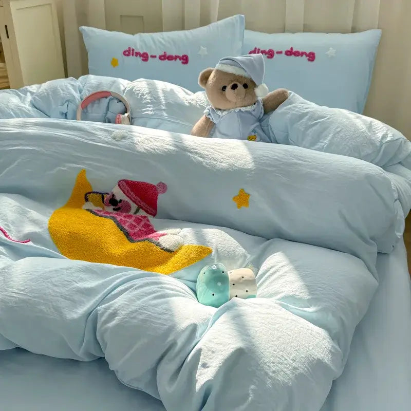 Light blue quilted bedding set with decorbites cartoon towel embroidery featuring a yellow crescent moon and pink character