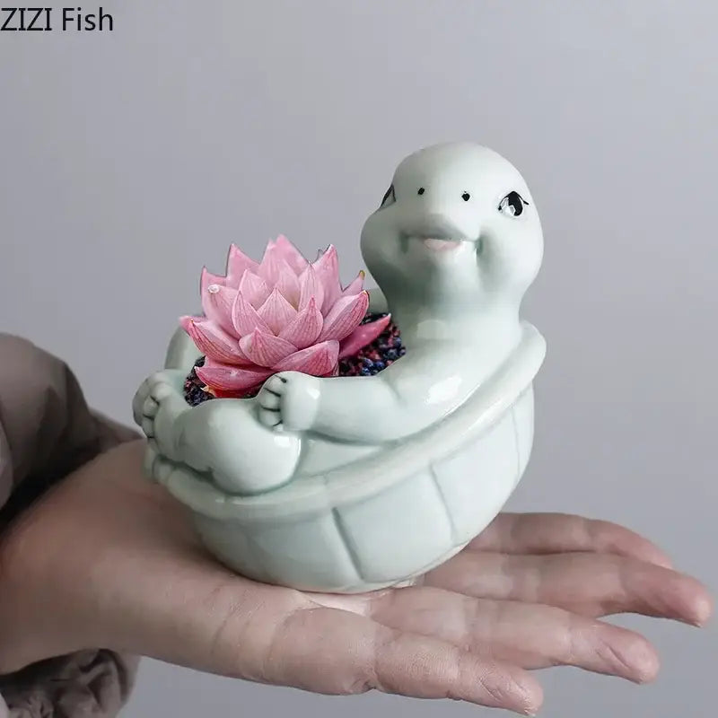 A light green cartoon turtle ceramic planter with a smiling face holding a pink lotus succulent for living room decor