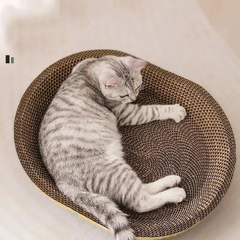 A gray tabby cat rests in a round brown and yellow corrugated cardboard cat scratch lounge bed in a living room setting