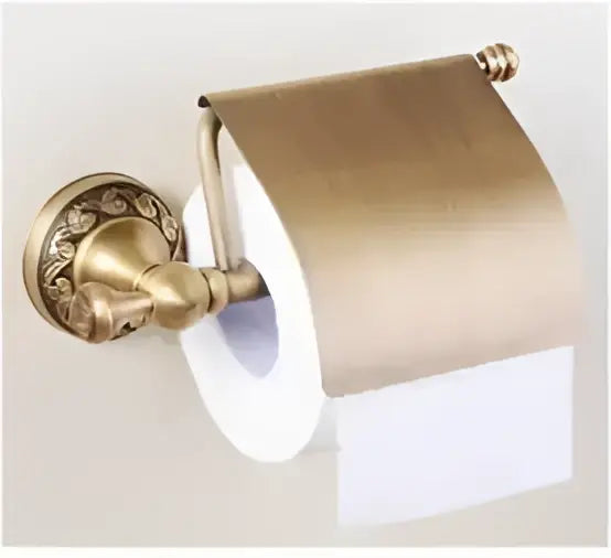 Antique bronze brass toilet paper holder with carved antique ornate scrollwork and a rolled white tissue roll