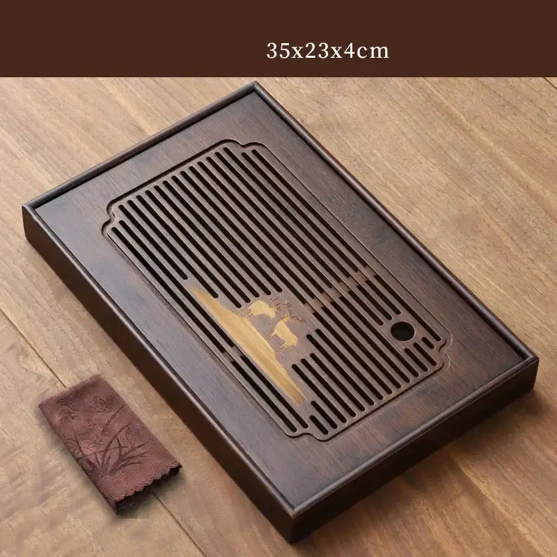 Dark brown bamboo tea tray with slatted drainage area and engraved golden deer motif for dining room use