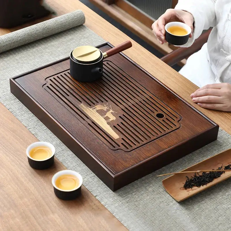 Dark brown bamboo tea tray with carved deer design and slatted drainage area for dining room use