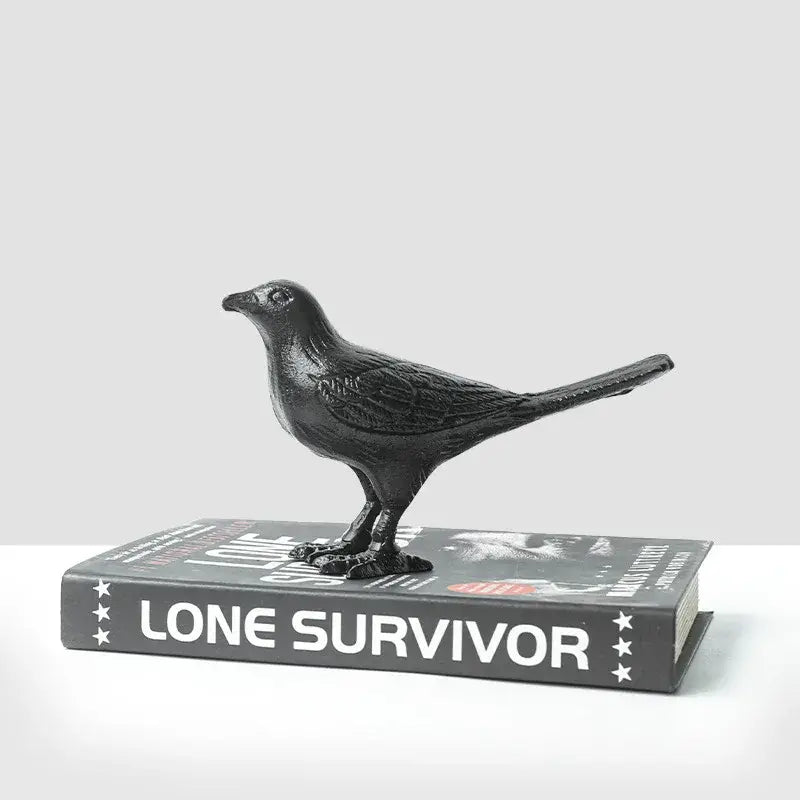 Black matte cast iron bird decoration perched on a book for elegant living room decor and iron bird display