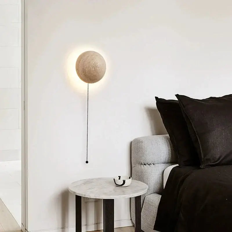 Beige spherical wall lamp with textured cave stone yellow surface and black pull chain for decorbites cave stone ambiance