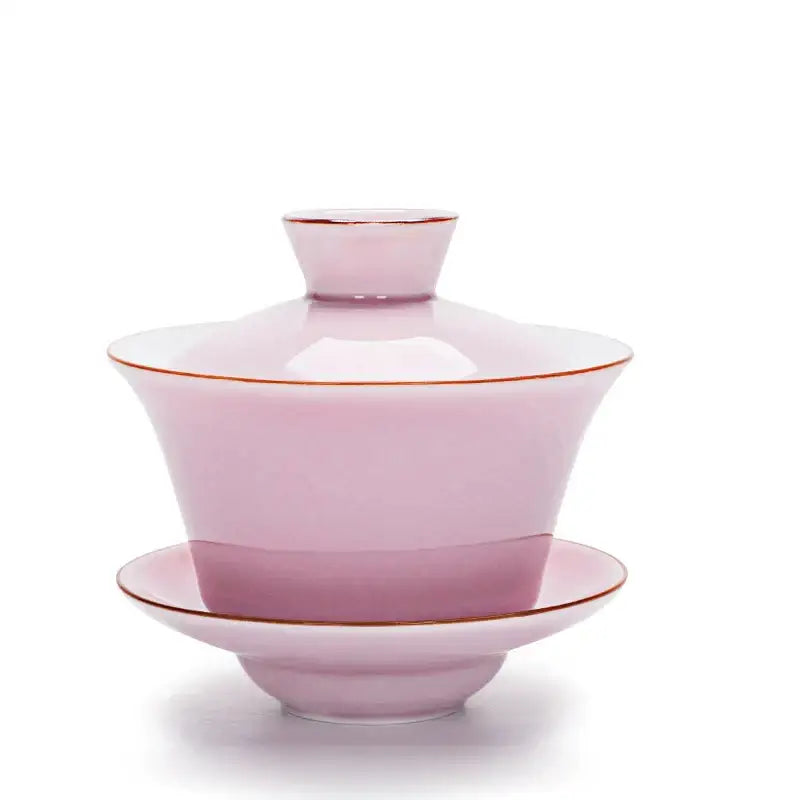 A delicate pink ceramic gaiwan with gold trim paired with a celadon tea tureen tea set for dining room use